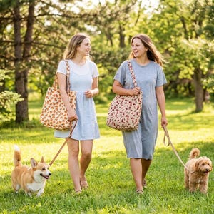 May include: Two people walking dogs in a park. They are carrying tote bags with floral and heart patterns. The dogs are on leashes. The scene is set on a sunny day with green grass and trees.