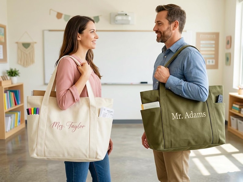 May include: Two canvas tote bags, one cream and one olive green, are held by a woman and a man. The cream bag has "Mrs. Taylor" in cursive, and the green bag has "Mr. Adams". Both bags have multiple pockets.