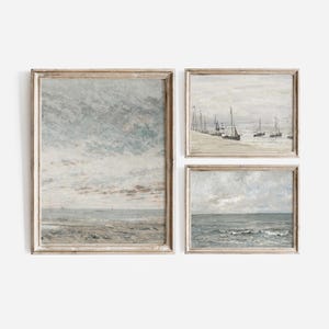 May include: Three framed paintings depicting seascapes. The top left painting shows a cloudy sky over a sandy beach. The top right painting shows a group of sailboats on a calm body of water. The bottom painting shows a stormy sea with waves.