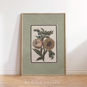 May include: A framed botanical print featuring a vintage illustration of a sunflower and a rose with green leaves and stems on a cream background. The frame is a light green color.
