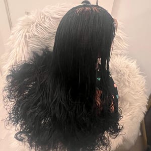 May include: Black micro braid wig with long, wavy ends. The wig is styled with a center part and is set on a fluffy, white faux fur chair. The hair is a deep black color, and the ends have a natural, curly texture.