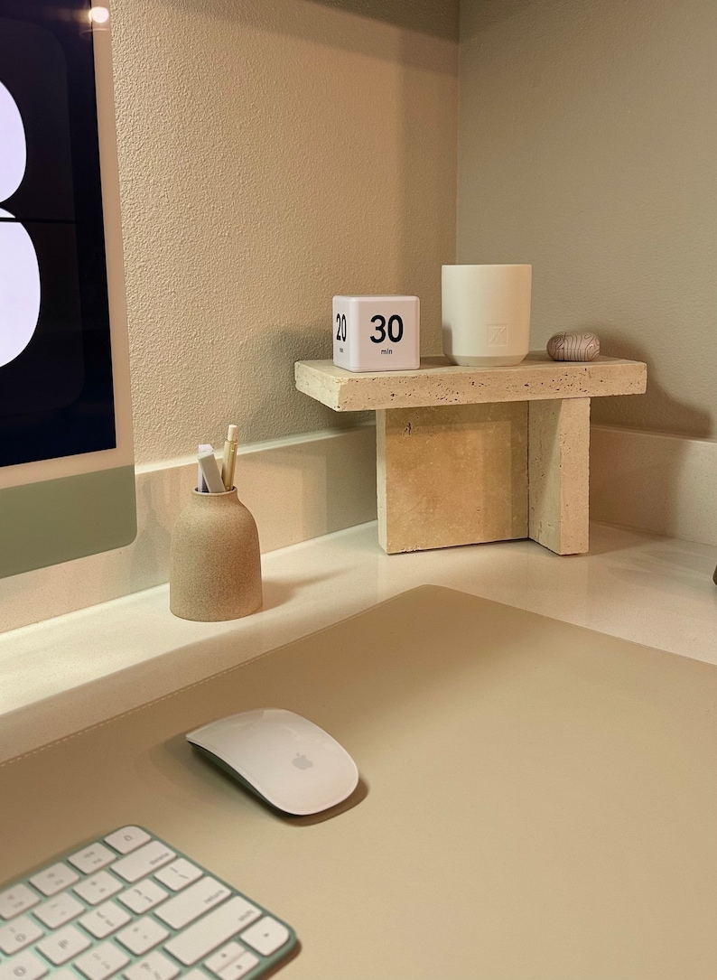 May include: A white desktop with a beige mouse pad, a white wireless keyboard with green keys, a white wireless mouse, a small beige ceramic vase with pencils, a white cube timer with the text "30 min", and a white ceramic candle on a beige stone shelf.