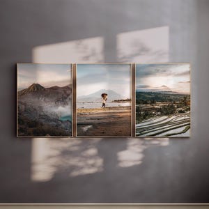 May include: A triptych of three framed landscape photographs. The left panel shows a volcanic crater with blue water. The center panel depicts a person carrying a load on a beach. The right panel displays terraced rice fields at sunset.