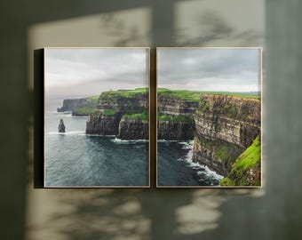 Peut inclure: Un ensemble d'art mural en diptyque composé de deux tirages encadrés des falaises de Moher. La photographie de paysage montre des falaises rocheuses escarpées brun foncé surmontées d'herbe vert vif, bordant l'océan bleu sous un ciel nuageux.