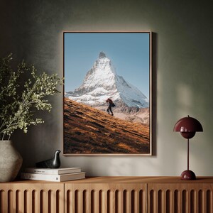 Elevate your home decor with this unframed Matterhorn wall art, encapsulating the essence of a solitary hikers journey in the Swiss Alps.