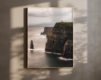 May include: A photograph of the Cliffs of Moher in Ireland. The cliffs are tall and dramatic, with a small building on top of the highest point. The ocean is a deep blue, and the sky is a light gray.