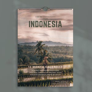 Könnte beinhalten: Ein Wandkalender mit Kunstfotografien aus Indonesien. Das Titelbild zeigt eine Landschaft mit Reisterrassen, Palmen und einem fernen Vulkangipfel unter einem bewölkten Himmel. Der Text lautet: FINE ART PHOTOGRAPHY FROM INDONESIA 12 MONTH CALENDAR.