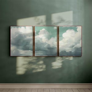 Peut inclure: Trois impressions encadrées d'un ciel nuageux dans un schéma de couleurs bleu clair et blanc. Les impressions sont disposées en rangée sur un mur vert.