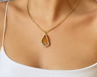 Puede incluir: Un collar de cadena dorada con un colgante de ágata marrón. El colgante tiene forma de lágrima con un borde áspero y natural.