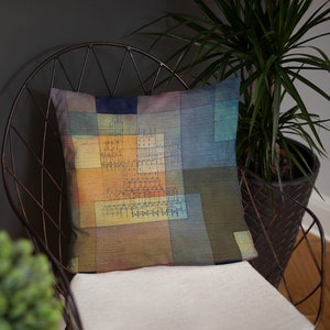 May include: A throw pillow with a geometric pattern in shades of blue, green, yellow, and orange. The pattern features a stylized cityscape with buildings and arches.