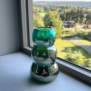 May include: A green glass vase with a metallic finish. The vase is made of three stacked, round pieces.