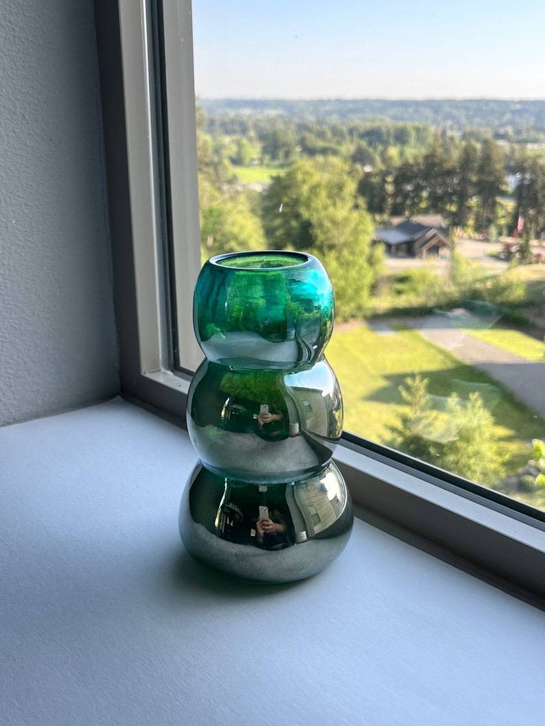 May include: A green glass vase with a metallic finish. The vase is made of three stacked, round pieces.