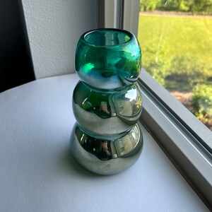 May include: A green glass vase with a metallic finish. The vase is made of three stacked, rounded pieces.