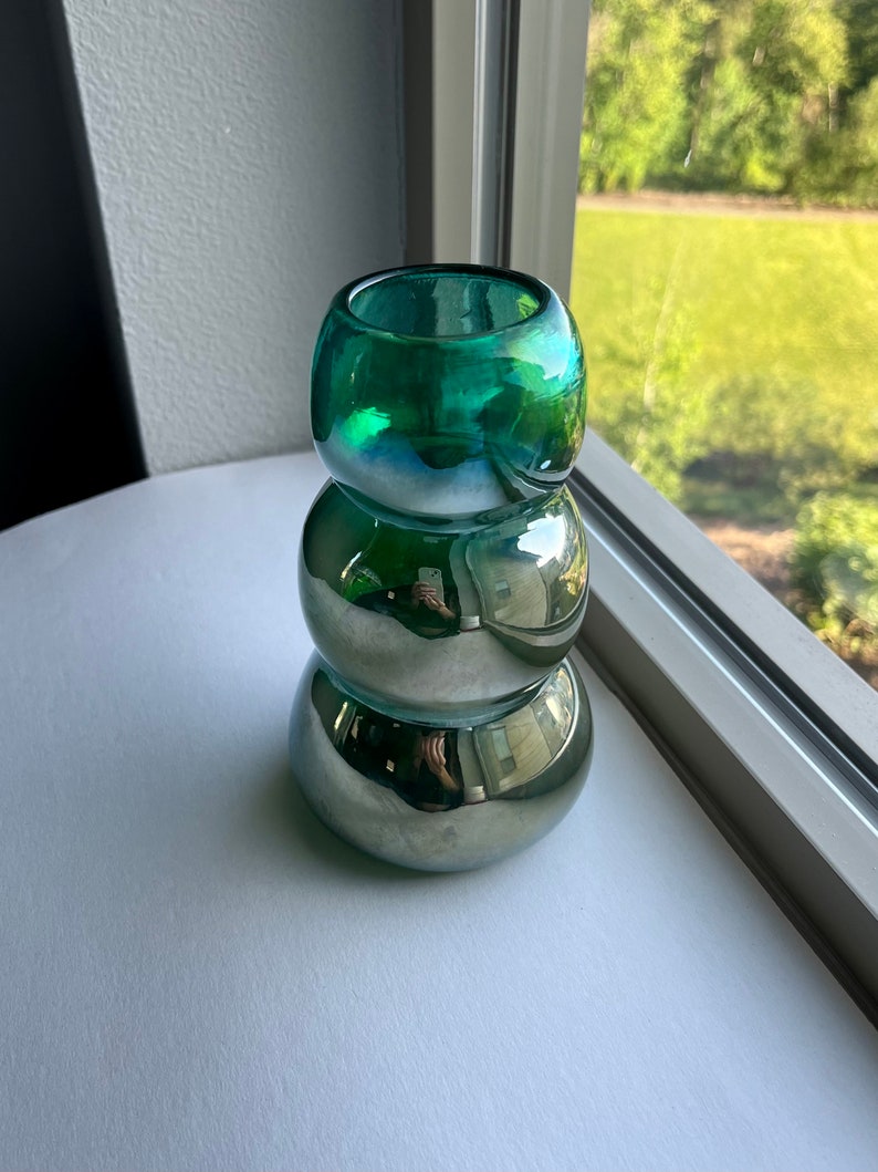May include: A green glass vase with a metallic finish. The vase is made of three stacked, rounded pieces.