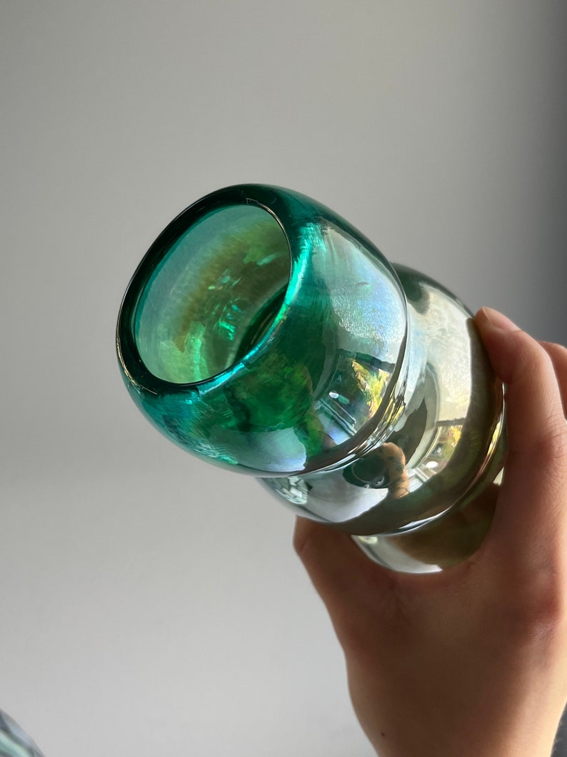 May include: A green glass bottle with a textured surface and a wide mouth opening.