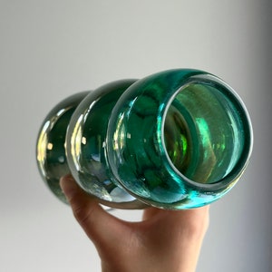 May include: A green glass vase with a rounded, bulbous shape. The vase has a smooth, glossy finish and is perfect for displaying flowers or other decorative items.