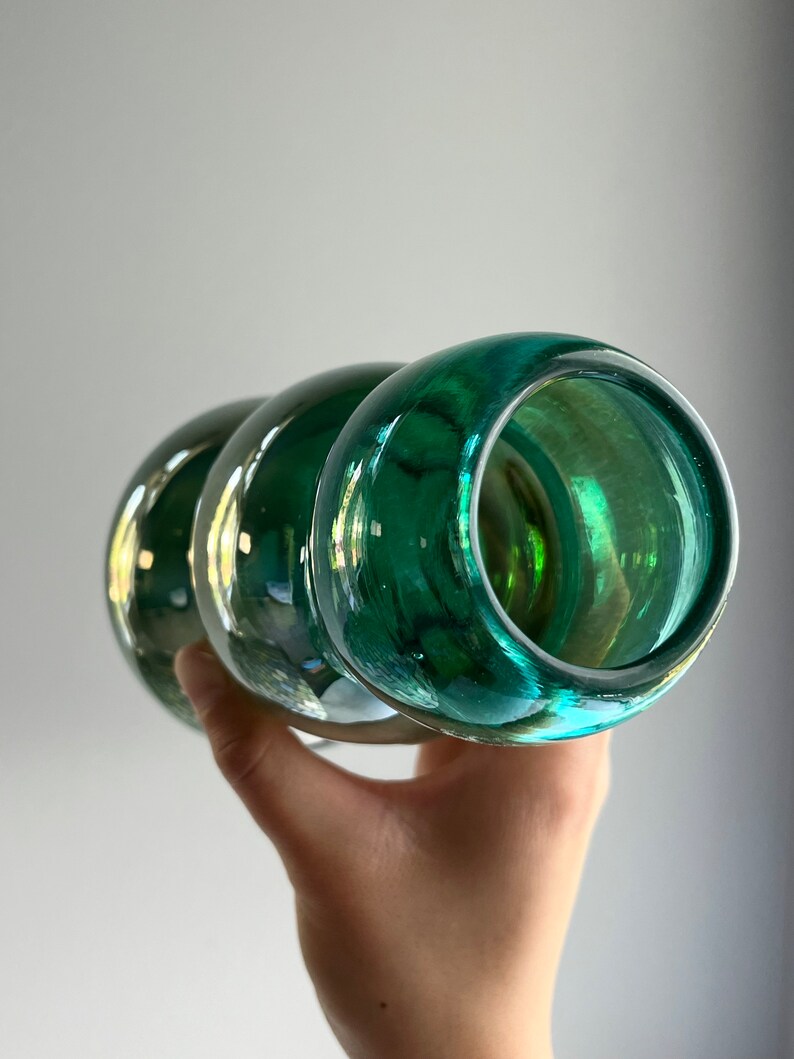 May include: A green glass vase with a rounded, bulbous shape. The vase has a smooth, glossy finish and is perfect for displaying flowers or other decorative items.