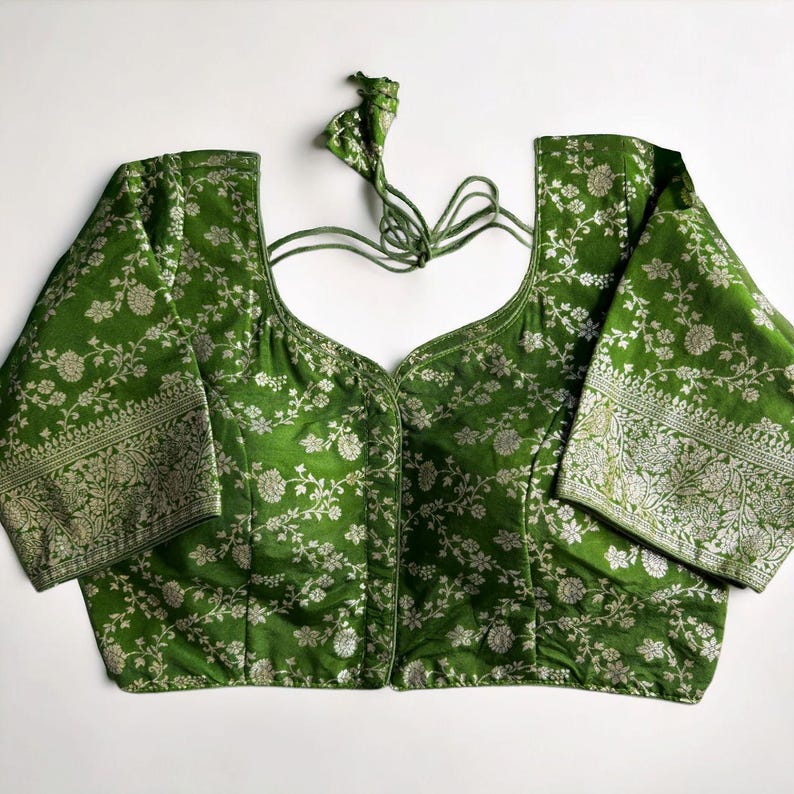 May include: A green brocade blouse with silver floral embroidery and a tie-up back.