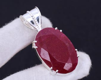 Può includere: Un ciondolo d'argento con una grande pietra preziosa di rubino di forma ovale e taglio sfaccettato. Il ciondolo ha una baionetta d'argento per fissarlo a una catena.