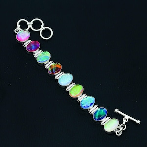 May include: A silver bracelet with a clasp and eight oval-shaped iridescent gemstones in shades of pink, blue, green, and purple.
