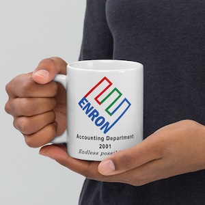 Könnte beinhalten: Eine weiße Keramiktasse mit einem blau-rot-grünen Logo, auf dem "Enron" steht, und dem Text "Accounting Department 2001 Endless possi...".