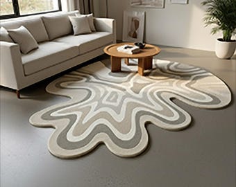 May include: A modern living room featuring a cream-colored sofa, a round wooden coffee table, and a unique rug. The rug has a wavy, abstract design in shades of gray and cream, adding a contemporary touch to the space.