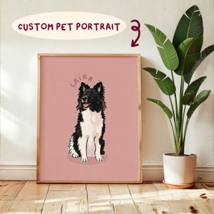May include: A framed custom pet portrait print featuring a black and white dog sitting on a solid dusty pink background. The name LAIKA is written in a curved arch above the dog's head in dark pink letters. The dog has a fluffy coat.