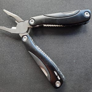 May include: Black multi-tool pliers with a silver blade and the text "MIL-TEC" on the handle.