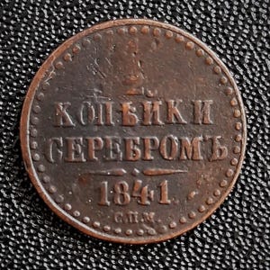 Może przedstawiać: Moneta miedziana z napisem "Копейка Серебромъ" i datą "1841" na niej.