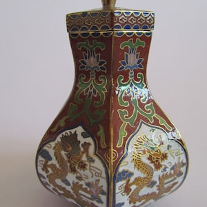 May include: A small, red, white and gold cloisonné vase with a hexagonal lid and a dragon design. The vase is decorated with floral patterns and has a gold-coloured top.