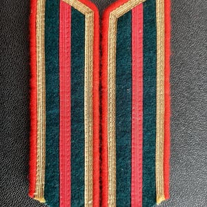 May include: Pair of dark green military shoulder boards with red and gold trim.
