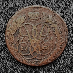 May include: A copper coin with a crown and the Cyrillic letters "A.P." surrounded by a wreath of leaves. The date "1761" is visible on the coin.