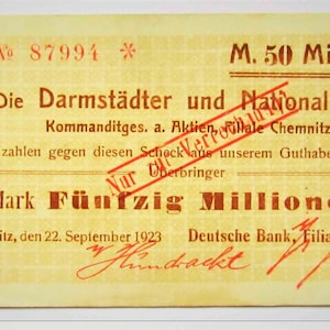 May include: A vintage German banknote from 1923, with German text. The note is yellowed, with red text and a red stamp reading "Nur Überbringer". The denomination is "Mark Fünfzig Millionen". The bank is "Die Darmstädter und Nationalbank".