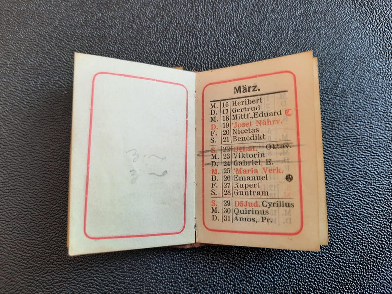 Puede incluir: Un peque&ntilde;o calendario vintage con un borde rojo. El calendario est&aacute; abierto al mes de marzo. Los d&iacute;as de la semana se abrevian como M, D, F y S. Los d&iacute;as del mes est&aacute;n numerados del 16 al 31. Cada d&iacute;a tiene un nombre asociado. El calendario est&aacute; impreso en tinta negra sobre papel blanco.