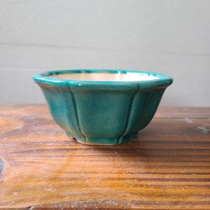 Op de afbeelding: Een turquoise keramische kom met een gegroefd ontwerp. De kom heeft een glanzende afwerking en een lichtgekleurd interieur. Hij staat op een houten oppervlak. De kom heeft een diameter van ongeveer 13 cm en is 8 cm hoog.