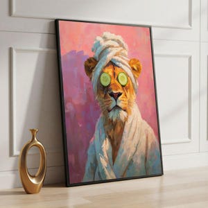 May include: Framed art print of a lion wearing a white towel on its head and a white robe, with cucumber slices over its eyes. The background is pink and purple. A gold vase is in the foreground.