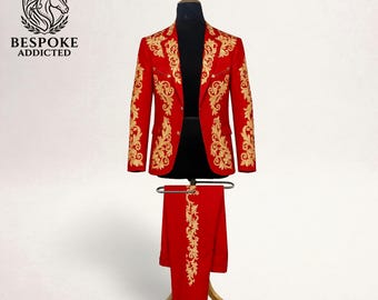 May include: A red suit with gold floral embroidery, displayed on a mannequin. The suit includes a jacket and matching pants. The jacket features ornate gold detailing along the lapels, sleeves, and front. The pants have a vertical gold floral design. The logo "BESPOKE ADDICTED" is visible.