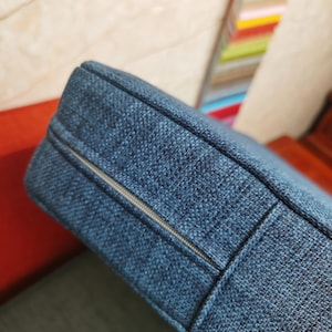 Puede incluir: Primer plano de un coj&iacute;n azul con una cremallera que recorre el borde. El coj&iacute;n est&aacute; hecho de una tela texturizada.