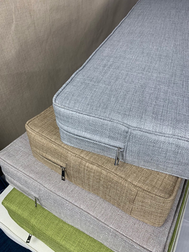 May include: Four stackable cushion covers in different colors and textures. The top cushion is light gray, the second is beige, the third is light gray, and the bottom is green. All cushions have zippers.