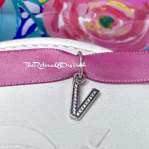 En caja de regalo, dije inicial de la letra V de Pandora para pulsera. Retirado y con marca registrada estampada.