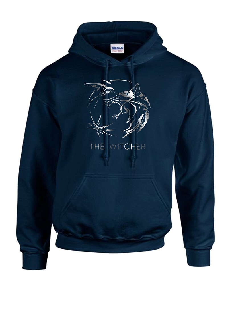 K&ouml;nnte beinhalten: Ein marineblauer Kapuzenpullover mit einem silbernen Wolf-Motiv und dem Schriftzug "THE WITCHER" auf der Vorderseite.