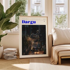 May include: A magazine cover with the title "Daegu" in blue text. The cover features a nighttime street scene with cars driving down a hill.
