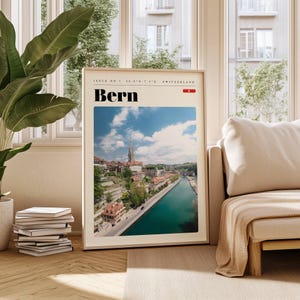 May include: A vintage-style poster with a photo of Bern, Switzerland. The poster has a white background with black text that reads "Issue No. 1 46.95°N 7.44°E Switzerland" and "Bern". The poster features a photo of a city with a river running through it.