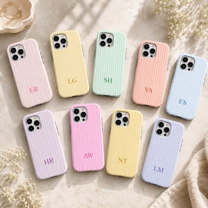 Puede incluir: Una colección de nueve fundas para teléfono en colores pastel con una textura acanalada vertical. Cada funda cuenta con un recorte para la cámara de triple lente y un monograma único de dos letras impreso en el centro inferior del reverso.