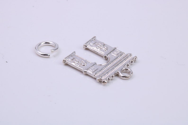 May include: Silver charm featuring a detailed design of an archway with a small loop at the bottom. A separate silver jump ring is also included.