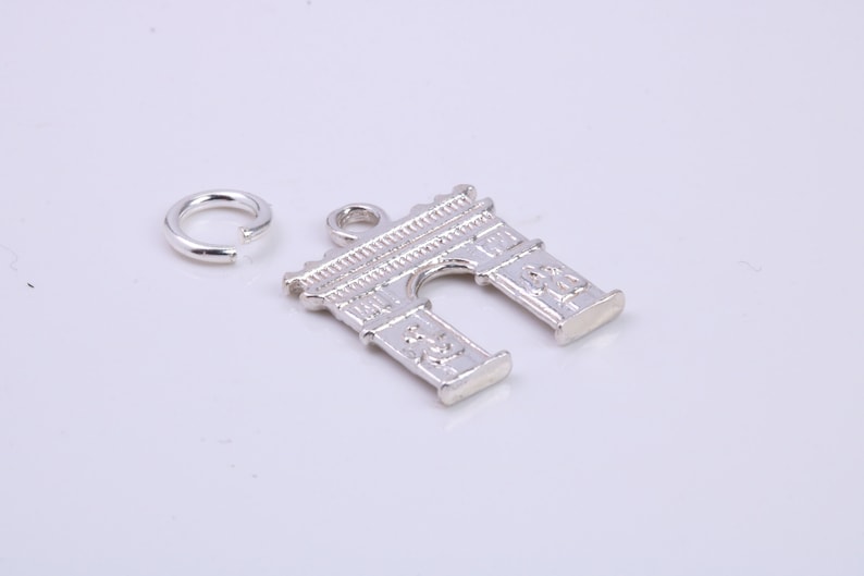 May include: Silver charm in the shape of an archway, with a small silver jump ring.