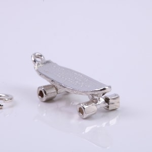 Puede incluir: Encanto de monopatín de plata con un bucle para sujetarlo a un collar o pulsera. El encanto está detallado con una plataforma de monopatín texturizada y ruedas.