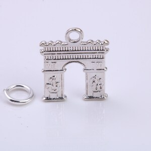 May include: Silver charm in the shape of the Arc de Triomphe, a famous Parisian landmark. The charm has a loop at the top for attaching to a bracelet or necklace.