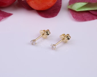 May include: A pair of gold stud earrings with small, clear cubic zirconia stones.