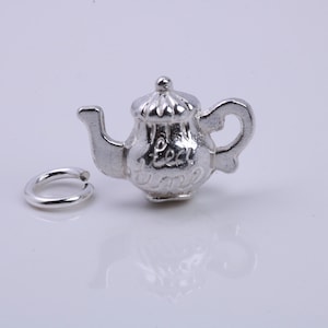 Puede incluir: Encanto de tetera de plata con un anillo adjunto. La tetera tiene una tapa y un asa y dice "Tea Time" en el lateral.